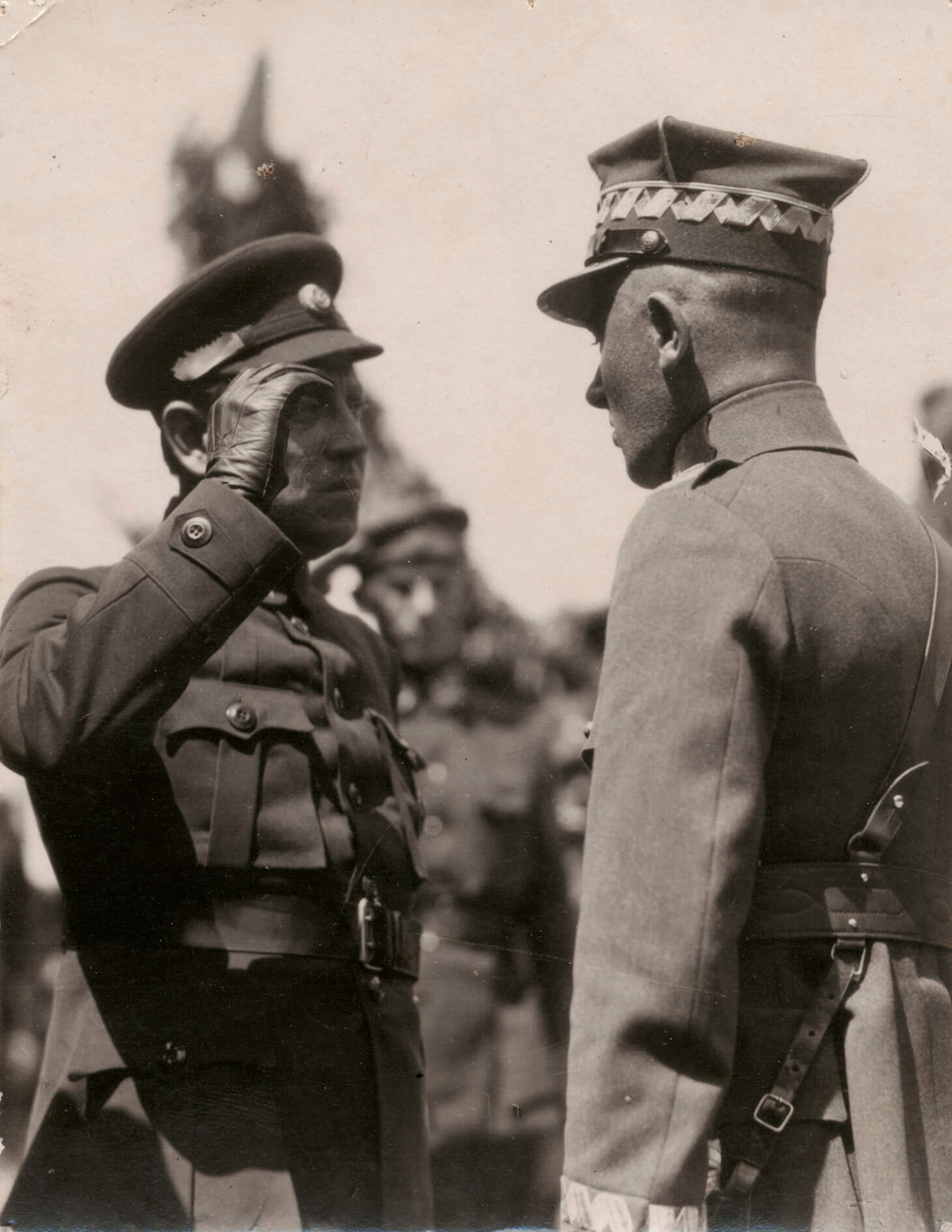 Czarno-biała fotografia przedstawiająca atamana Symona Petlurę salutującego generałowi Edwardowi Śmigłemu-Rydzowi. Sylwetki obu żołnierzy, w ujęciu półpełnym , od pasa w górę, wypełniają cały kadr. Po lewej, w ciemnym mundurze znajduje się ataman Symon Petlura, a po prawej  generał Edward Śmigły-Rydz, odwrócony lewym ramieniem do widza. widzianemu w takim ujęciu nieco od tyłu. W tle, nieostry zarys trzeciego salutującego żołnierza. 