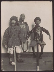 Czarno-białe zdjęcie przedstawia trzy lalki, kukiełki na trzonkach. Postaci uformowane są z różnego rodzaju gałganów. Kukła,pierwsza po lewej stronie stylizowana jest na postać chłopa, druga po lewej, w drugim planie stylizowana jest na postać o rysach azjatyckich, z ogoloną głową i cienkim warkoczykiem. Kukła trzecia od lewej, stylizowana jest na bolszewika w skórzanej kurtce spiętej paskiem z kaburą na pistolet, w bryczesach i wysokich butach.

